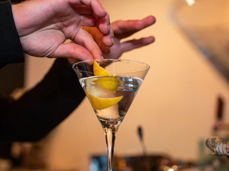 Someone adds a twist of lemon to their DIY cocktail.